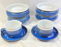 Four blue Denby Chatsworth bowls stacked two by two, sugar bowl and creamer each placed on blue saucers