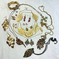 Photo showing full assortment of gold tone jewelry including necklaces, earrings, bracelets, and brooches spread on a white background.