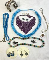 Wide view of all jewelry items including necklaces, earrings, and bracelet laid out on white surface