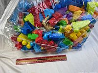 Large clear plastic bag filled with colorful Mega Bloks pieces showing mixed blocks and animal figurine.