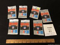 Seven 1991 Upper Deck NFL Quarterback Challenge football card packs arranged on black background alongside a ruler and MaxSold sign. Six packs unopened, one opened.