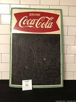 Full front view of the vintage Drink Coca-Cola fiberboard menu chalkboard with visible wear and scratches on the black chalkboard area.