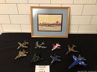 Lot showing framed photo and 8 toy jet planes on black surface