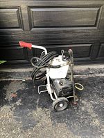 Front side view showing the unit mounted on a wheeled frame with handle and coiled hose.