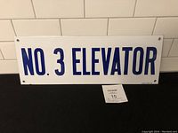 Front view of enamel sign showing text 'NO. 3 ELEVATOR' with mounting holes and good condition.