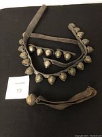 Full view of all sleigh bells on leather straps including one single bell on a hand strap, displayed on black background.