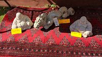 Photo showing all three cement statues placed on a patterned rug: two Buddha statues on either side and a dragon statue in center with size notes.