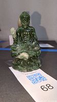 Front view of green resin Buddha statue, showing detailed facial features and right hand raised