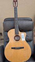 Full front view of Taylor 114ce acoustic guitar leaning against chair