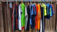 Full view of rack with assorted men's shirts and shorts in various bright and dark colors.