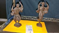 Photo of two metal Japanese dancing figurines on a yellow backdrop, showing their size and general appearance.