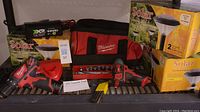 Overview of lot showing Milwaukee cordless drill, impact wrench, drill bits, tool bag and solar garden lights boxes