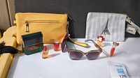 Full lot including bags, sunglasses, and perfumes arranged on surface in natural light