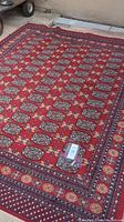 Full view of red Majal Place rug with geometric and floral motifs and fringe on one end.