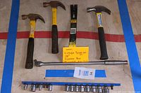 Full view of all tools: three claw hammers, crowbar, Snap-on breaker bar, socket wrench, and socket set on blue rail.