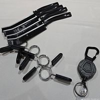 Photo showing four black clamps, four black and white cleaning brushes, and one black retractable keychain.