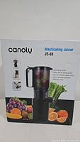 Front view of the boxed Canoly JE-68 masticating juicer showing branding, model, and product features.