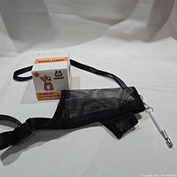 Photo showing boxed puppy teething toy and black mesh adjustable mouthguard with metal clasp attached.