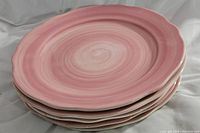Stack of five pink Franciscan Flora Rosa charger plates with swirled glaze and scalloped edges.