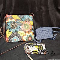 Three Vera Bradley items: one large floral print shoulder bag and two wallets, one navy quilted and one multicolored floral