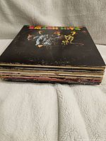 Stack of multiple vintage vinyl records lying flat showing worn edges and covers.