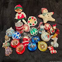 Full view of the entire lot including a rag doll elf, snowman, Campbell's soup can for size reference, assorted colorful glass ball ornaments, beaded bells and angels, small Santa figure, and various fabric and felt decorations.