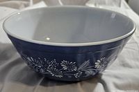 Front side view of the vintage Pyrex Colonial Mist blue bowl with white floral design.