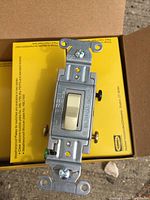 Close-up photo of a single Hubbell CS315I 3-way switch showing ivory toggle, metal mounting bracket, and electrical rating markings.