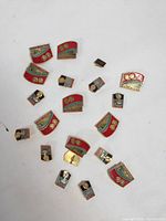 Photo showing majority of the 20 vintage USSR Donetsk pins and badges laid out on a white surface, highlighting red and blue enamel colors and Soviet motifs.