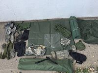 Various military mats, bags, pouches, and other gear laid out on the ground showing different brands, colors, and sizes.