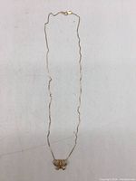 Full length of necklace with butterfly pendant laid flat on light surface