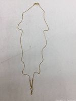 Full view of delicate yellow gold chain with pendant on plain surface.