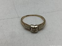 Front view of the ring showing the white gold square setting with a small diamond centered and engraved yellow gold band.