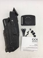 Safariland black textured holster with attached belt loop and separate hardware with instructions laid out on white surface