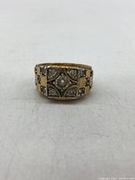 Front view of vintage gold tone ring with clear rhinestones in geometric pattern on top face.