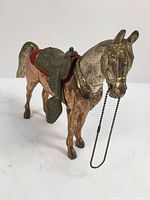 Front and left side view showing the overall horse figurine, the saddle details, red cloth, and metal chain rein.