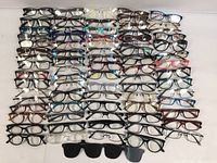 Front view of a collection of 55 eyeglasses and optical frames arranged in rows on a flat surface showing various frame shapes and colors.
