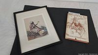 Framed print and book laid flat showing the art and book cover.