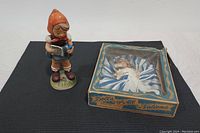 Arnart Music Time Girl figurine standing next to the 1950's Israel Doll of All Nations in its original box.