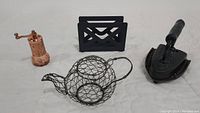 Full lot view showing handmade Turkish brass spice mill, black metal napkin holder, antique iron with base, and wire teapot holder