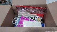 Box filled with assorted gift bags showing various patterns and colors, packed loosely.