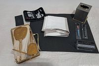 Full view of all included bathroom items showing vintage gold-tone vanity set, shower curtain, manicure set, tissue box cover, makeup brushes, and rings.