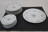 Stack of small and medium plates with floral pattern and gold edge detail set on black mat