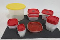 Overview of 14 Rubbermaid plastic storage containers with red and yellow lids arranged on a dark fabric mat.