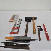 Top view showing all items laid out including hammers, wrenches, files, clamps, level, pipe cutter, and razor blades.