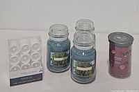 Overview of all items included in lot: three blue Willow Breeze candles, one red Peppermint Pinwheels candle, and a pack of 12 flameless LED votives.