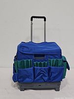 Photo of blue rolling collapsible craft tote with external blue and green pockets and retractable handle