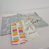 Set of linens including two tea towels, two pillow sham covers, and a folded grey table runner laid out for display