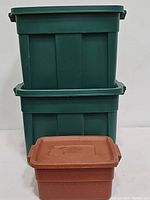 Two large green plastic totes stacked with one smaller brown tote in front, showing entire group of totes included in lot.