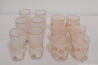 Photo showing 12 vintage plastic tumblers: 6 tall clear plastic tumblers with coral and white seashell decoration and 6 shorter coral orange seashell patterned tumblers.